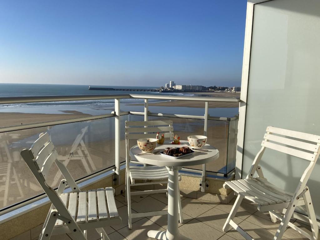 une table et des chaises sur un balcon avec vue sur l'océan dans l'établissement Bel Appartement face mer - GARAGE, à Les Sables-dʼOlonne