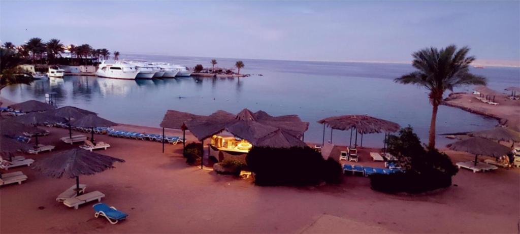 une plage avec des parasols et des bateaux dans l'eau dans l'établissement ZYA Regina Resort and Aqua Park Hurghada, à Hurghada