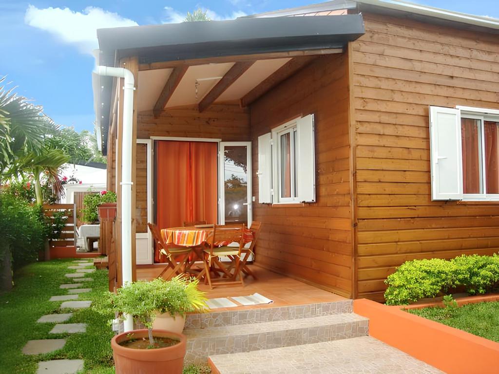 eine kleine Holzhütte mit einem Tisch und einer Terrasse in der Unterkunft Maison de 2 chambres avec vue sur la mer jardin clos et wifi a Saint Paul a 7 km de la plage in Saint-Paul