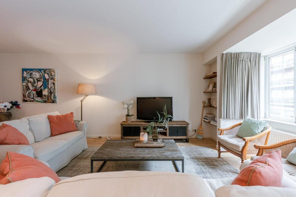 a living room with a couch and a tv at Huswell - Apartment on top location in Knokke with parking in Knokke-Heist