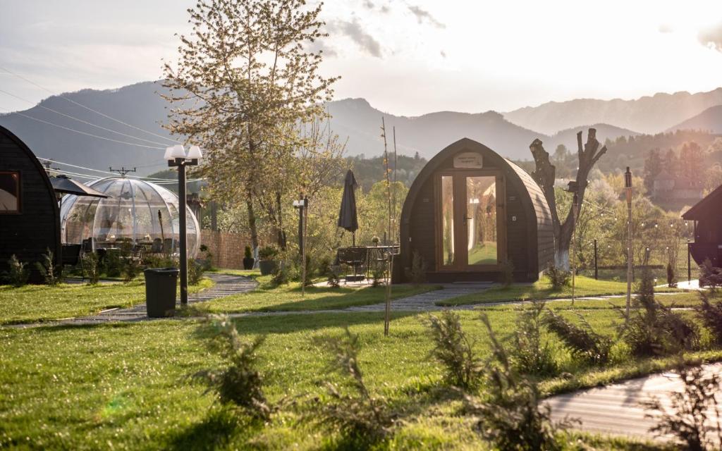 a small greenhouse in a garden with mountains in the background at Glamp In Style Pods Resort in Bran