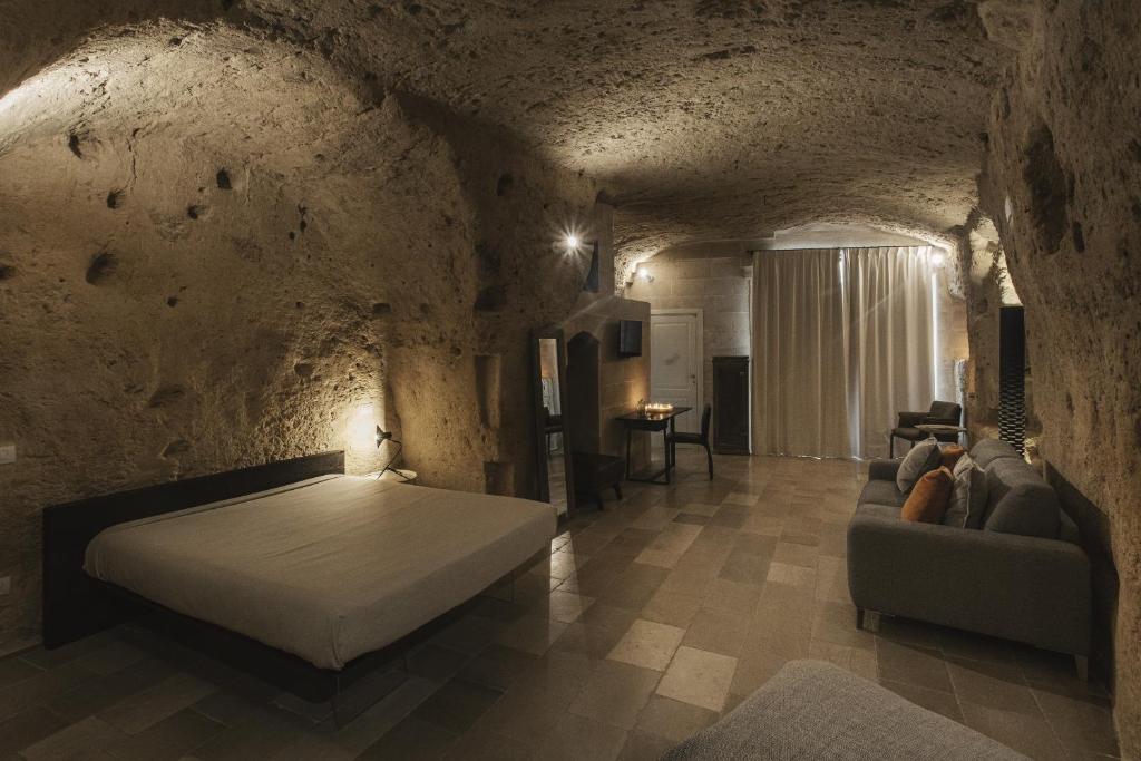 a bedroom with a bed and a couch in a stone wall at Aque cave in Matera
