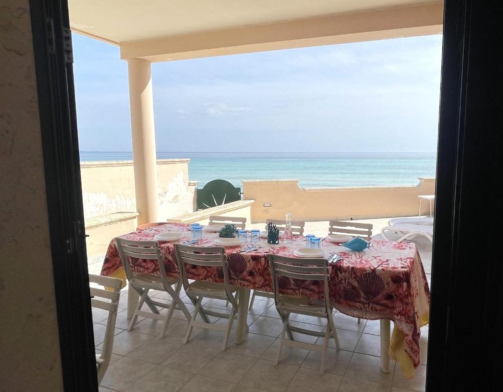 una mesa con sillas y vistas al océano en Villa Ciccarese dentro la spiaggia, en Porto Cesareo