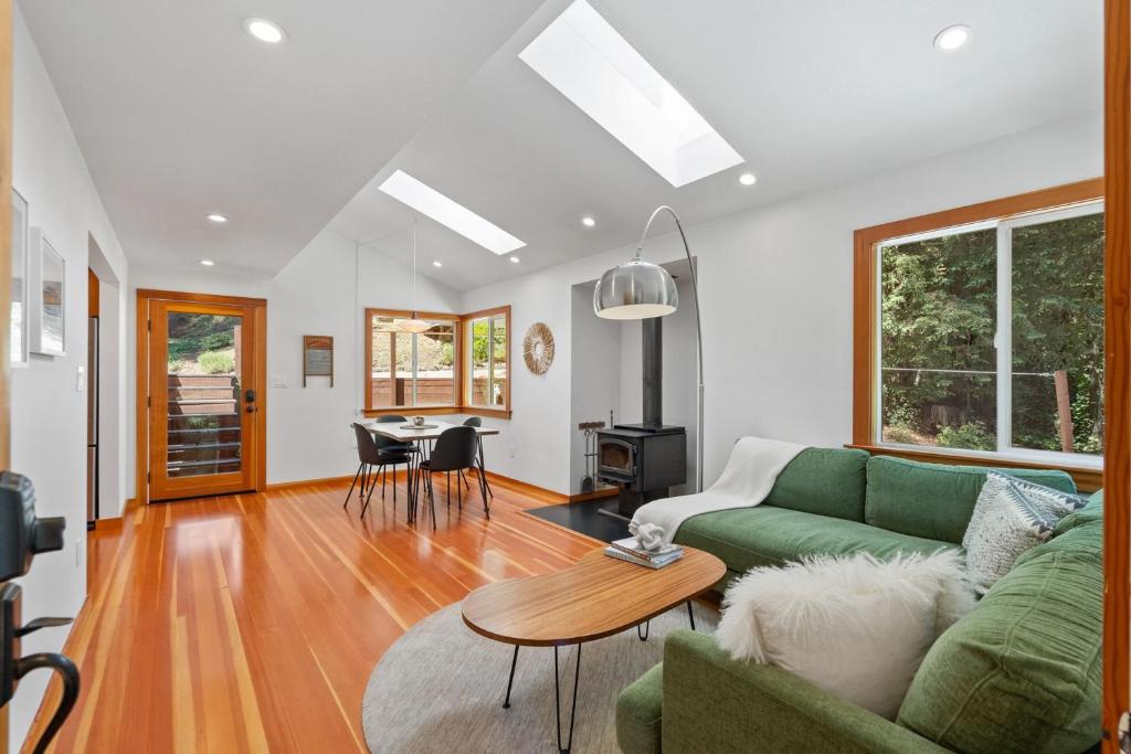 a living room with a green couch and a table at Redwood Oasis - Eco-luxury cabin with hot tub in the Santa Cruz Mountains in Ben Lomond