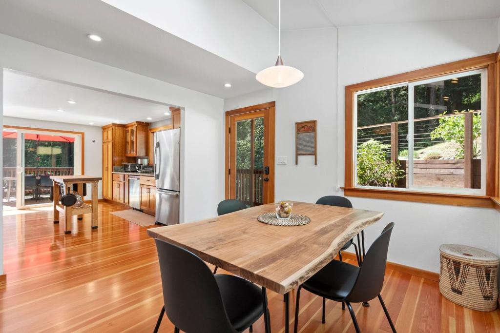 a kitchen and dining room with a wooden table and chairs at Redwood Oasis - Eco-luxury cabin with hot tub in the Santa Cruz Mountains in Ben Lomond
