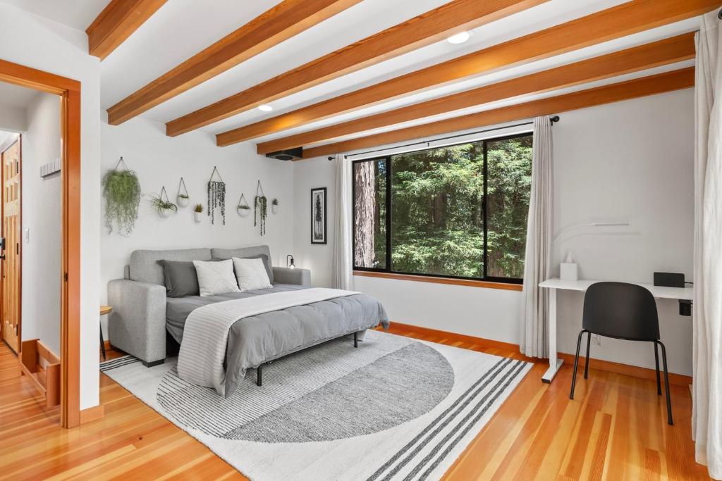 a bedroom with a bed and a desk and a window at Redwood Oasis - Eco-luxury cabin with hot tub in the Santa Cruz Mountains in Ben Lomond