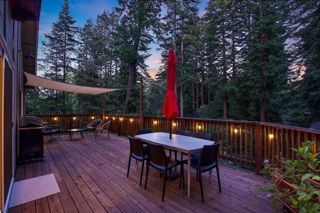a deck with a table and chairs and a umbrella at Redwood Oasis - Eco-luxury cabin with hot tub in the Santa Cruz Mountains in Ben Lomond