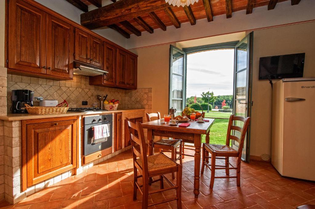 kuchnia ze stołem, krzesłami i lodówką w obiekcie Casa Vacanze La Fiorita w mieście Cortona
