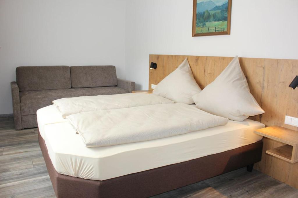 a bed with white sheets and pillows in a room at Mesnerwirt in Neukirchen am Teisenberg