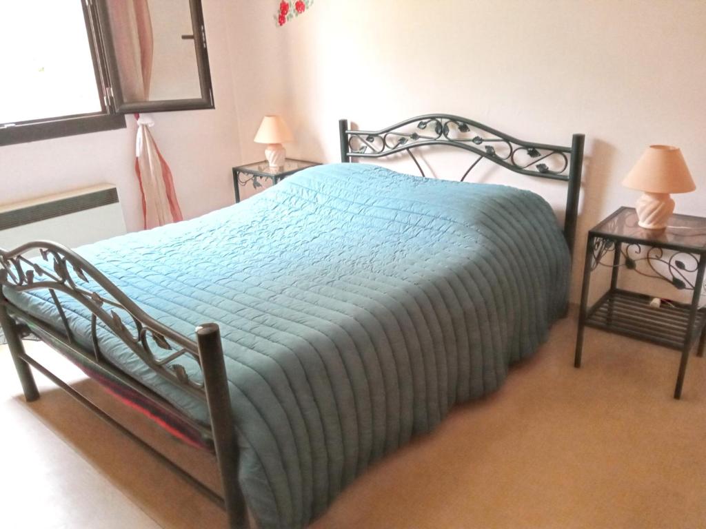 - une chambre avec un lit avec une couverture bleue et 2 tables dans l'établissement Appartement de 2 chambres avec vue sur le lac et jardin clos a Fontrabiouse a 7 km des pistes, à Fontrabiouse