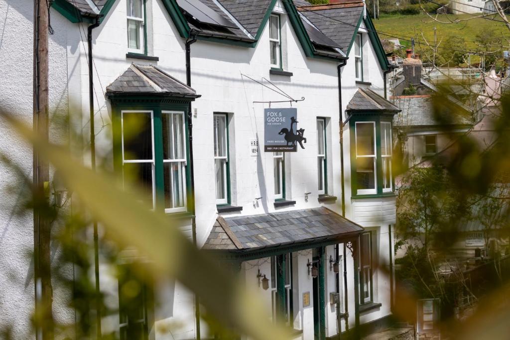 The Fox and Goose في Parracombe: صف من البيوت البيضاء مع نوافذ خضراء