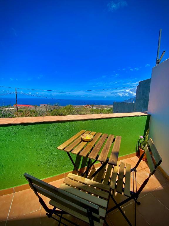 een houten tafel en stoel op een balkon met een groen veld bij ApKanariooo in Frontera