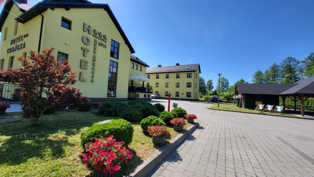 Hotel Chańcza في Raków: مبنى أمامه زهور ونباتات