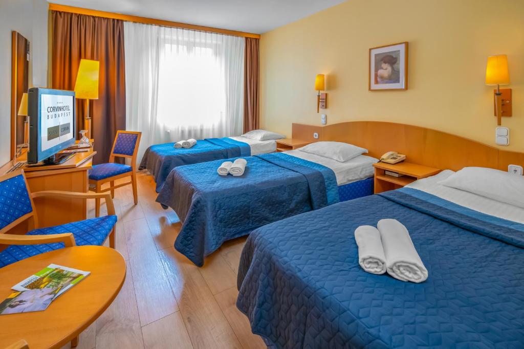 um quarto de hotel com três camas e uma televisão em Corvin Hotel Budapest Sissi Wing em Budapeste