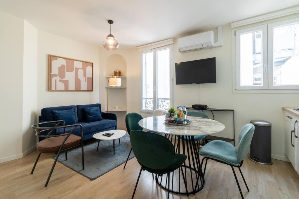 Una sala de estar con una mesa y un sofá azul. en B3#Two Bedrooms#Champs Elysées#Arc de Triomphe#AC, en París
