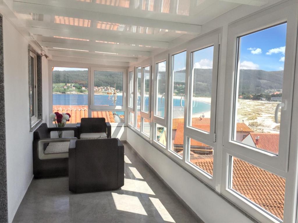 ラシェにある2 bedrooms apartement at Laxe 80 m away from the beach with sea view and furnished terraceの大きな窓、ソファ、椅子が備わる客室です。