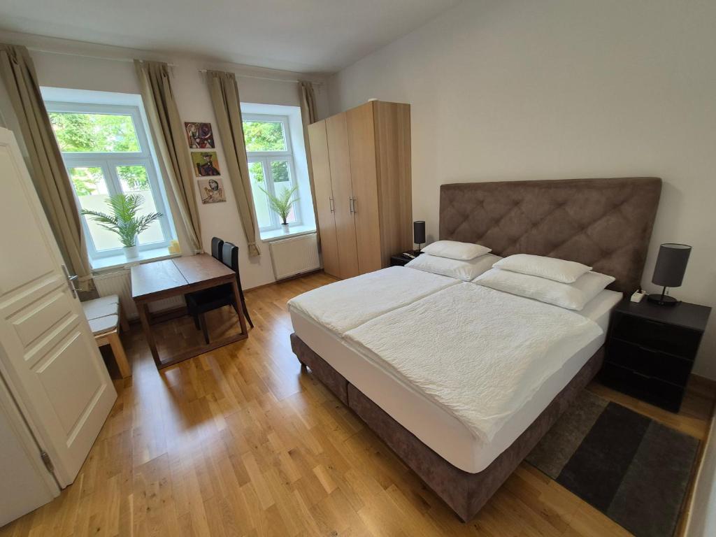 een slaapkamer met een bed, een bureau en 2 ramen bij Sweet Dreams in Wenen