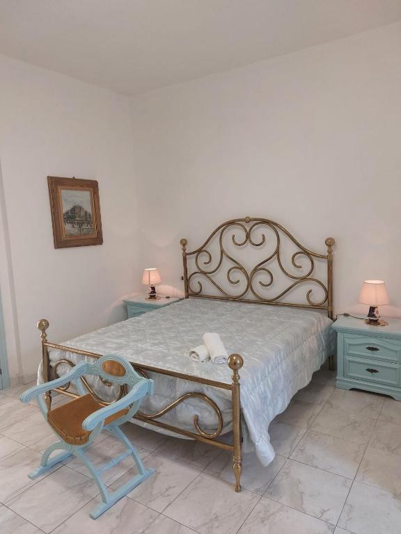a bedroom with a bed with a chair and two tables at La Maison de Lucietta in Lucera