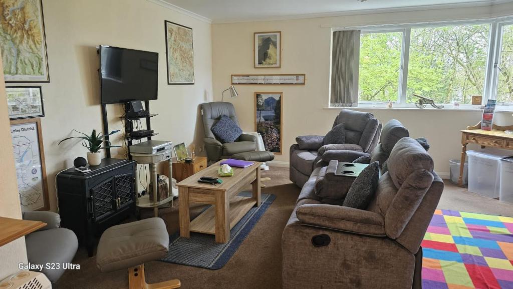 uma sala de estar com sofás e uma televisão em Howgill em Windermere