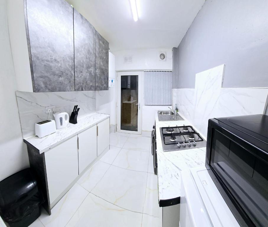 a kitchen with white counters and a stove top oven at 7 Guest 4 Bedrooms CITY CENTRE lovely home in Loughborough City Centre in Loughborough