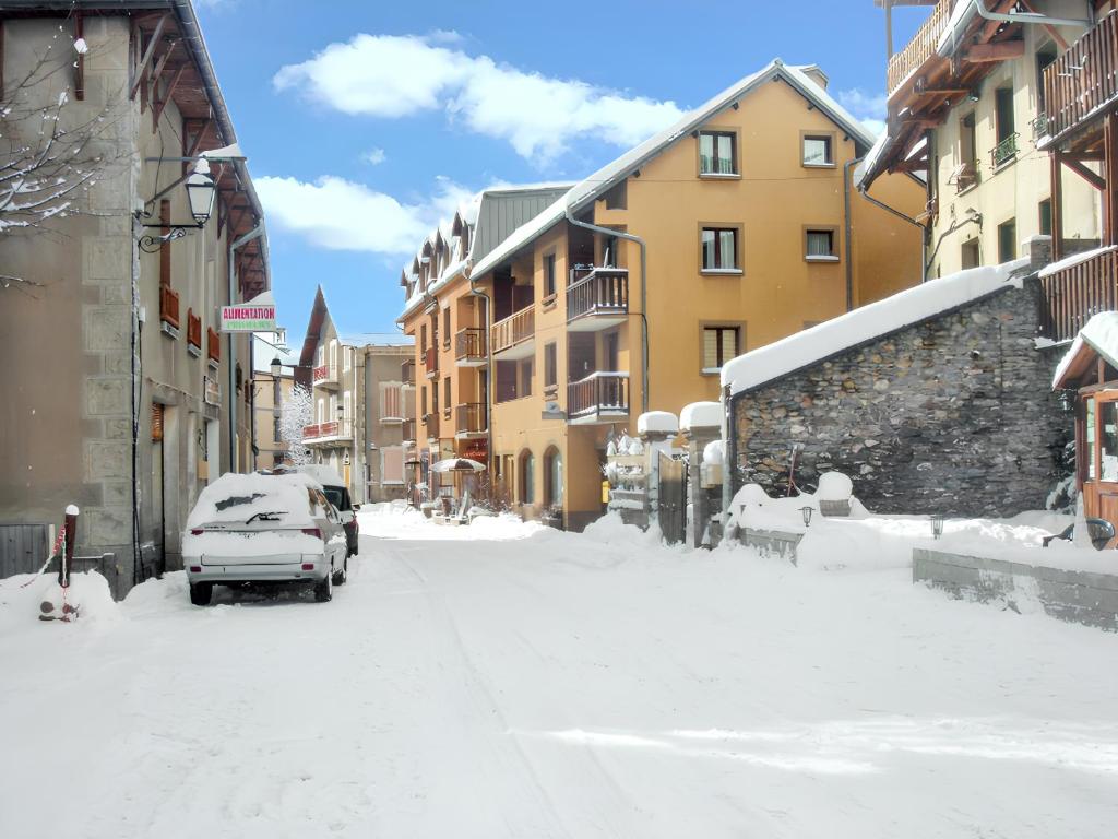 a snow covered street with buildings and a car parked at Studio a Aiguilles a 5 km des pistes in Aiguilles