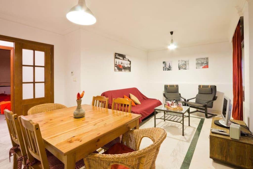 a living room with a wooden table and a red couch at Entre la Alhambra y Sierra Nevada in Monachil