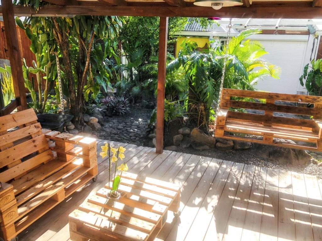 2 bancos de madera sentados en un patio con plantas en Appartement de 2 chambres avec jardin clos et wifi a Basse Terre en Basse-Terre