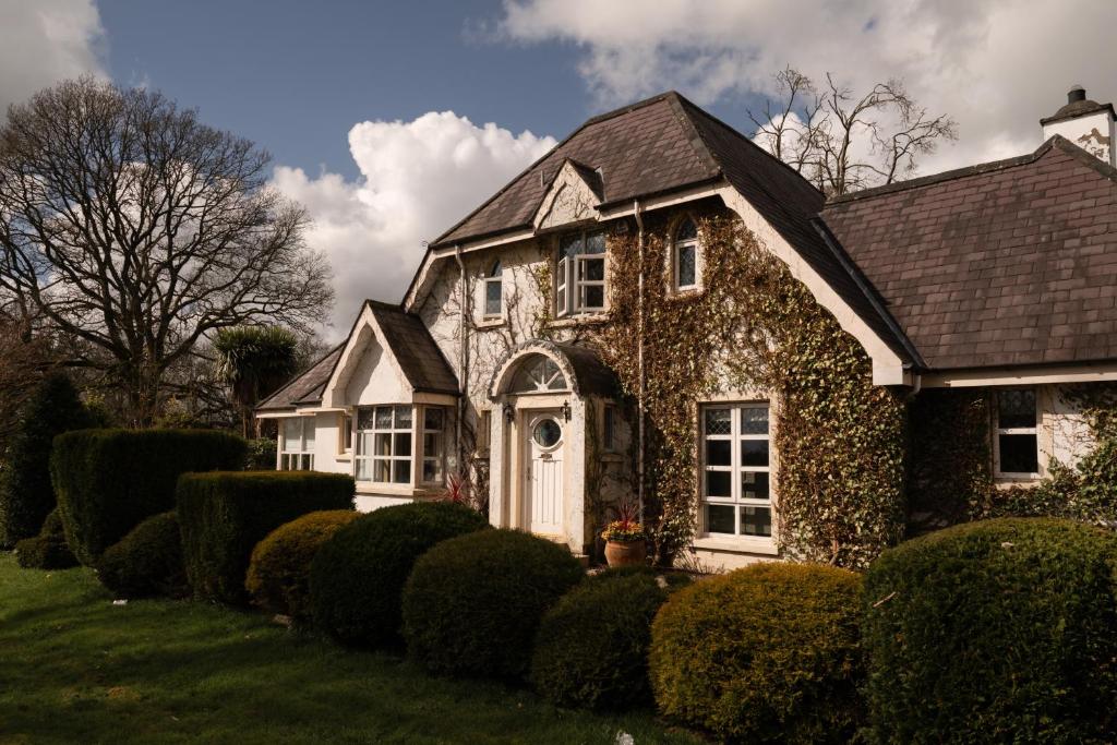 une maison en pierre avec des buissons devant elle dans l'établissement Galgorm, à Ballymena