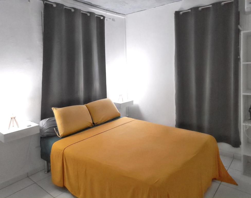 a bedroom with a bed with a yellow blanket at Appartement d'une chambre avec piscine partagee jacuzzi et jardin clos a Sainte Rose a 3 km de la plage in Sainte-Rose
