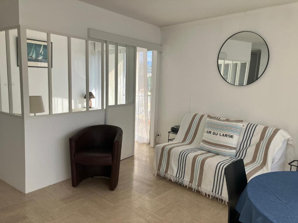 une chambre avec un lit, une chaise et un miroir dans l'établissement mandelieu, à Mandelieu-la-Napoule