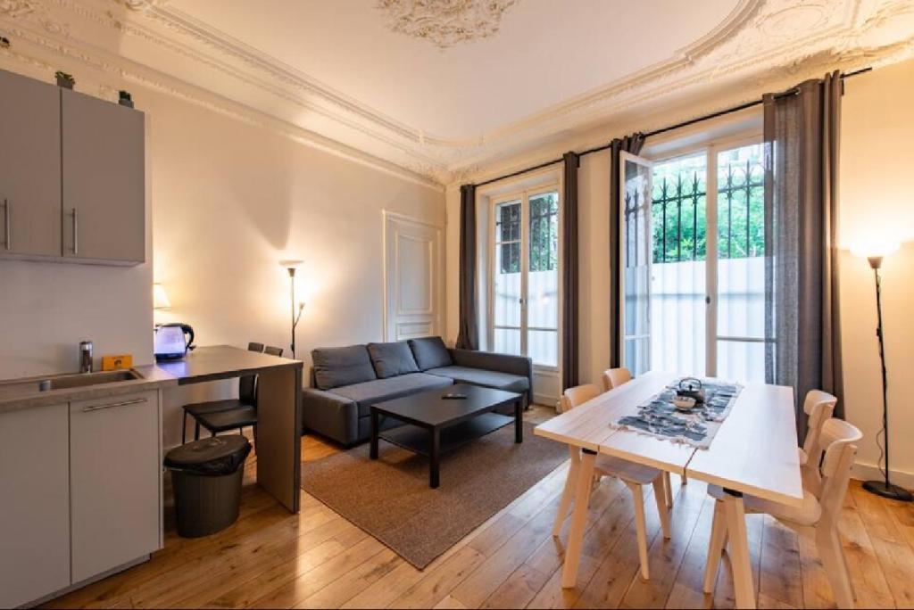 une cuisine et un salon avec une table et un canapé dans l'établissement Geranimus Morland : Hearth of Paris, à Paris