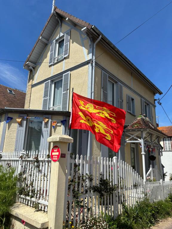une maison arborant un drapeau rouge devant elle dans l'établissement Villa Alcyon, à Lion-sur-Mer