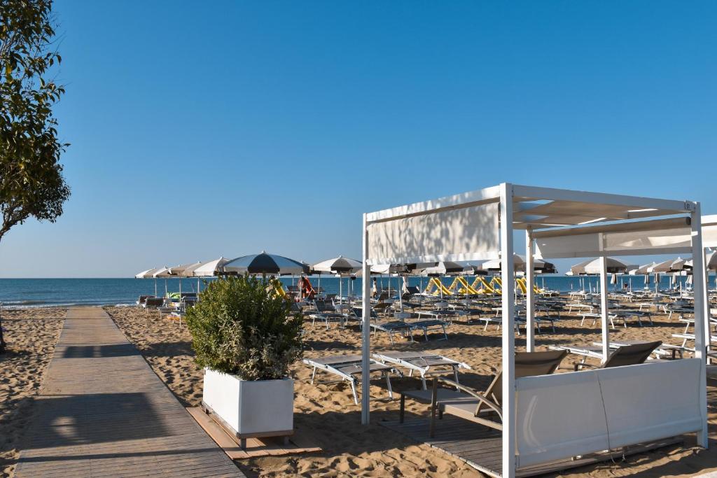 plaża z leżakami i parasolami oraz ocean w obiekcie Hotel Luna w Bibione