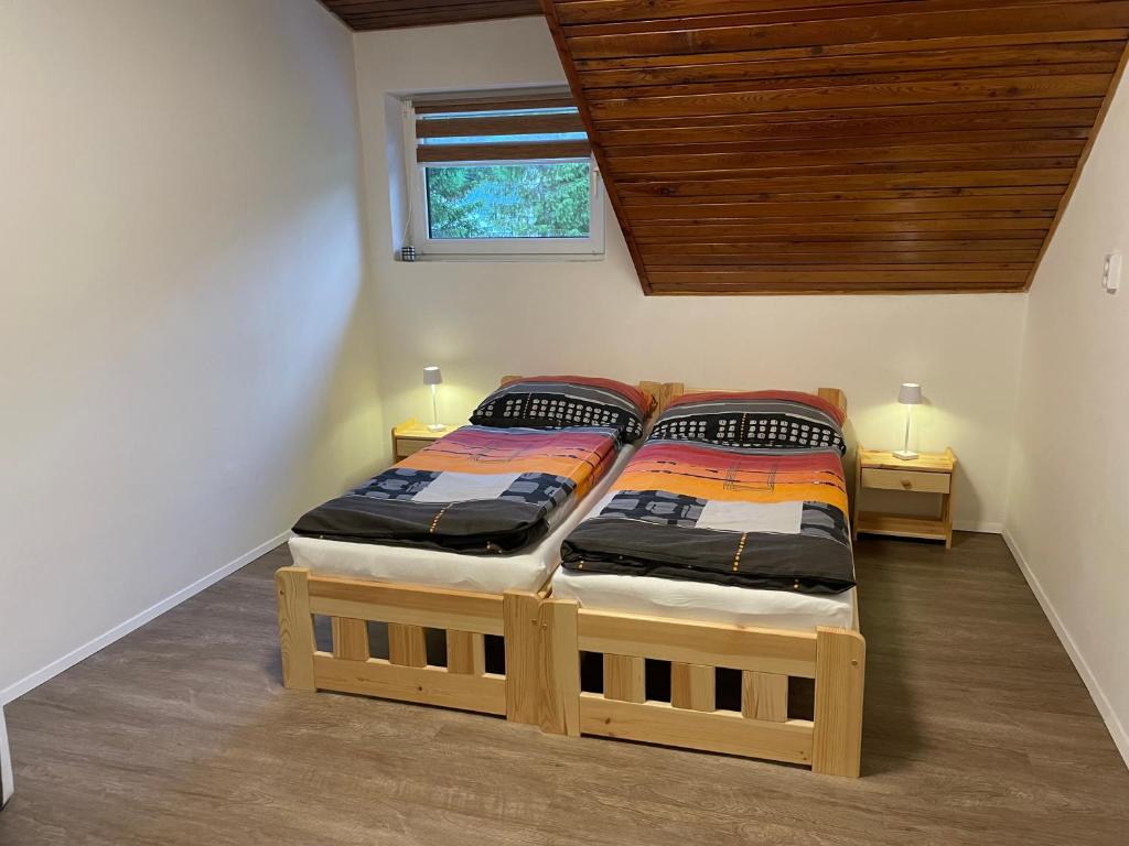 2 camas individuales en un dormitorio con techo de madera en Penzión Stratenka en Stratená
