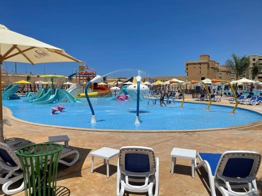 ein großer Wasserpark mit Stühlen und Sonnenschirm in der Unterkunft استديو فندقى مكيف فيو مميز بتراس AquaView in El Qasaba esh Sharqīya