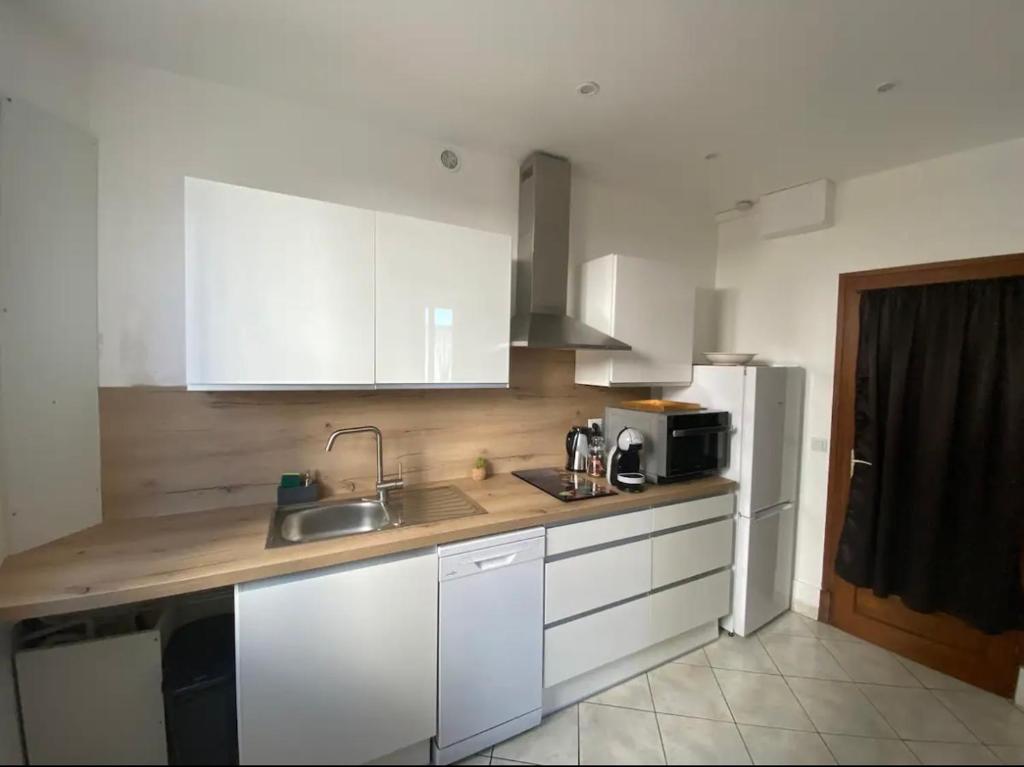 une cuisine avec des armoires blanches, un évier et un réfrigérateur dans l'établissement Meublés d'Anna, à Aix-les-Bains