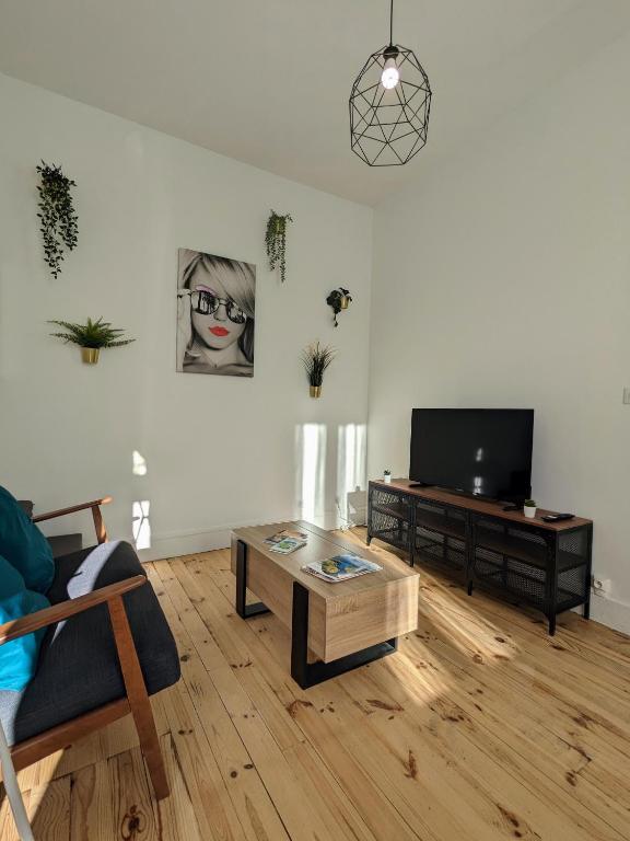 un salon avec une télévision et une table basse dans l'établissement La pause roannaise, à Roanne