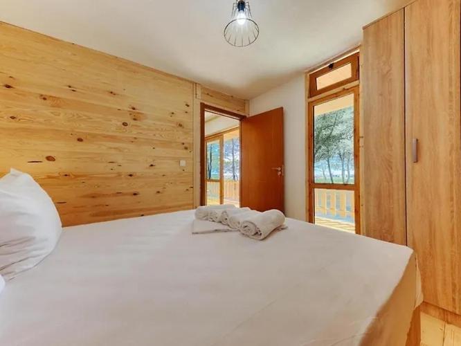 a large white bed in a bedroom with wooden walls at Imperial Family Bungalows in Ulcinj