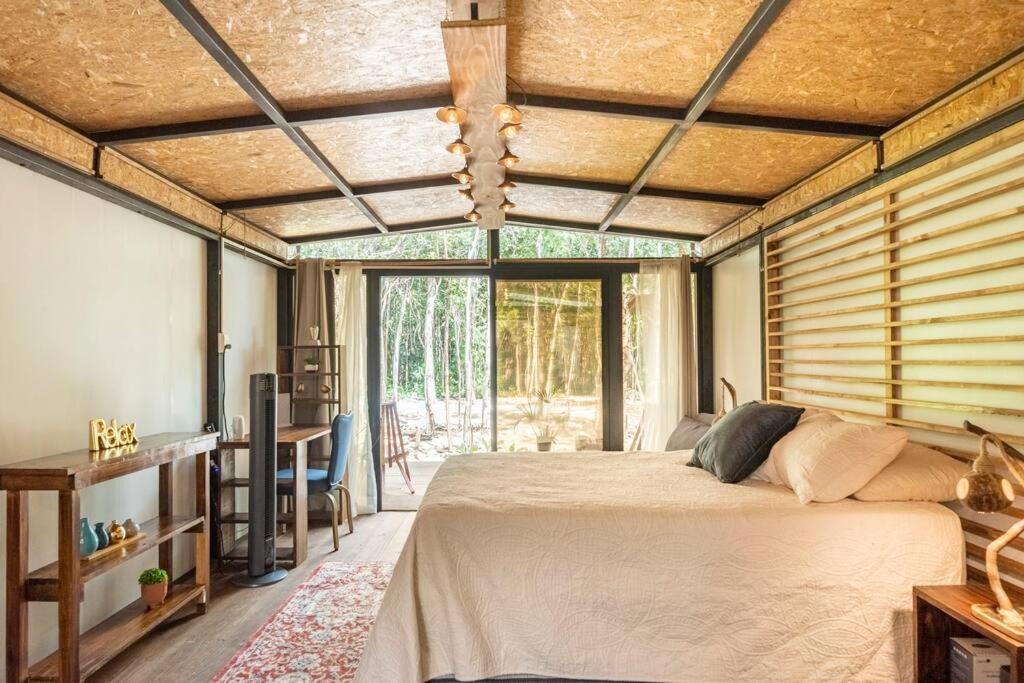 a bedroom with a bed and a large window at Zil-Kaab Hidden Glamping Village in Tulum