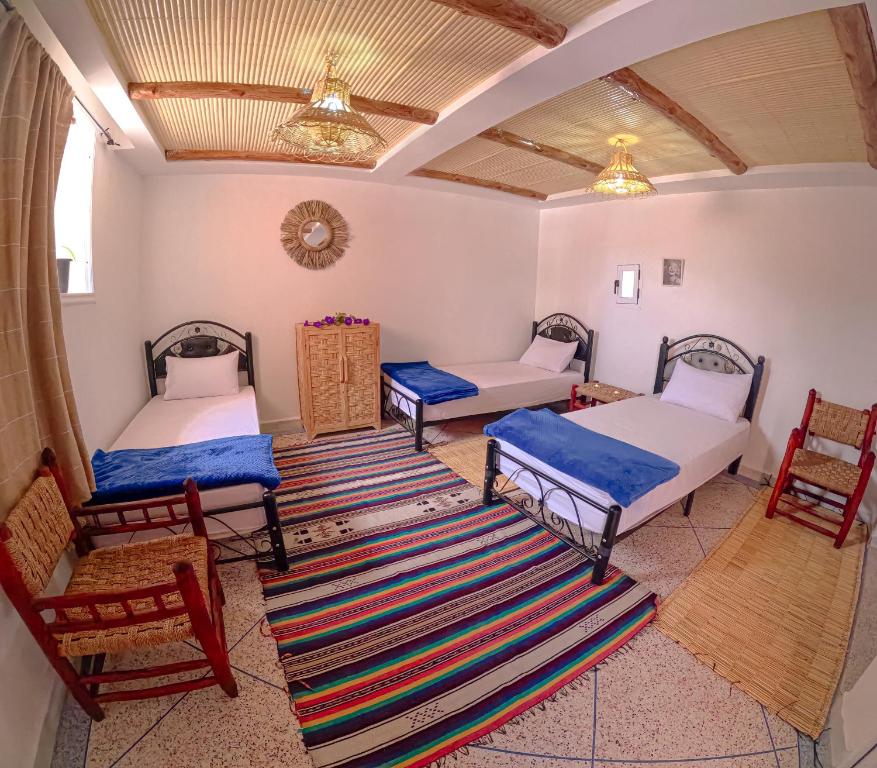 a room with two beds and two chairs at Riptide Surf House in Taghazout