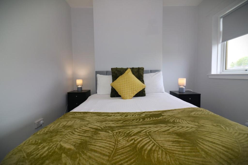 a bedroom with a large bed with a yellow pillow at Signature - Huntley House in Glasgow