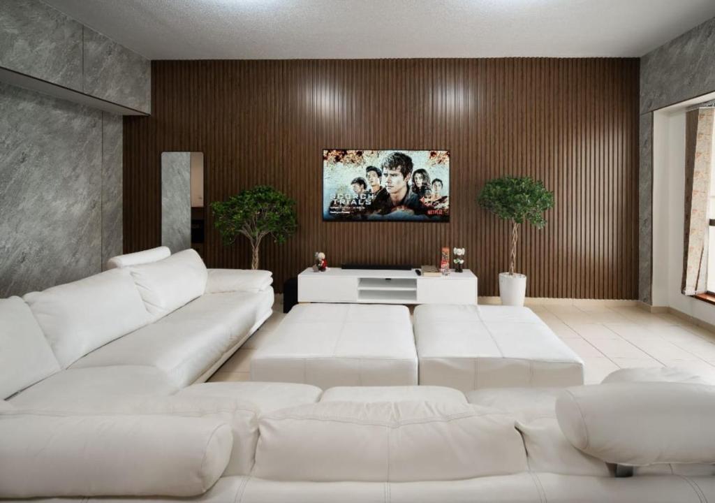 sala de estar con sofás blancos y TV en SleepandGO, en Dubái