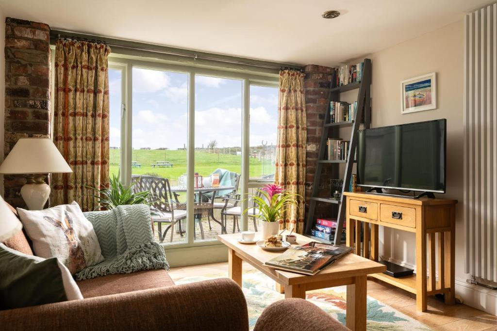 a living room with a couch and a television at The Byre, Heritage Escapes, Field House Farm in Bempton