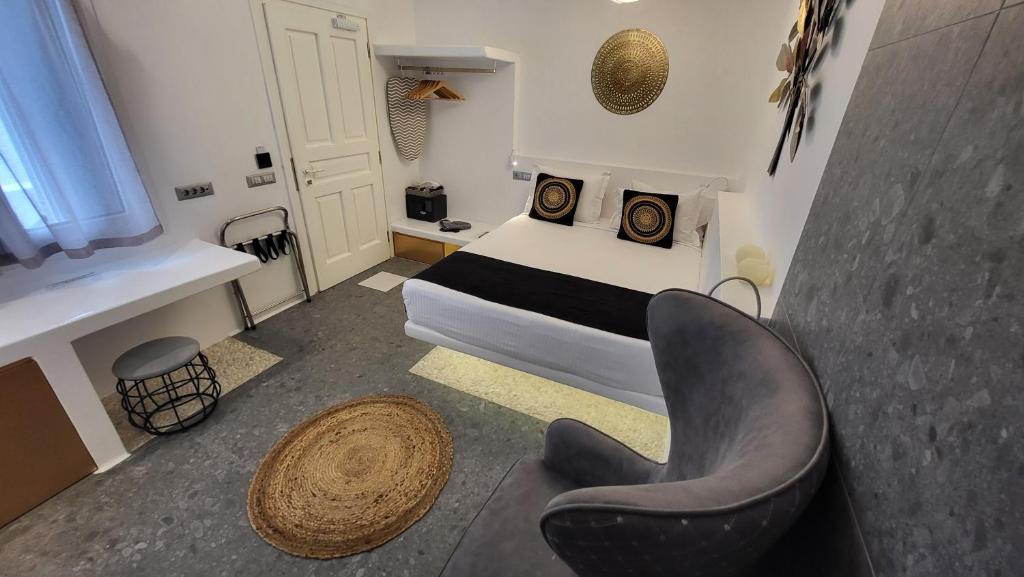 Mykonos Double Luxury Mini Suites - Adults only في أنو ميرا: غرفة نوم صغيرة بها سرير وكرسي