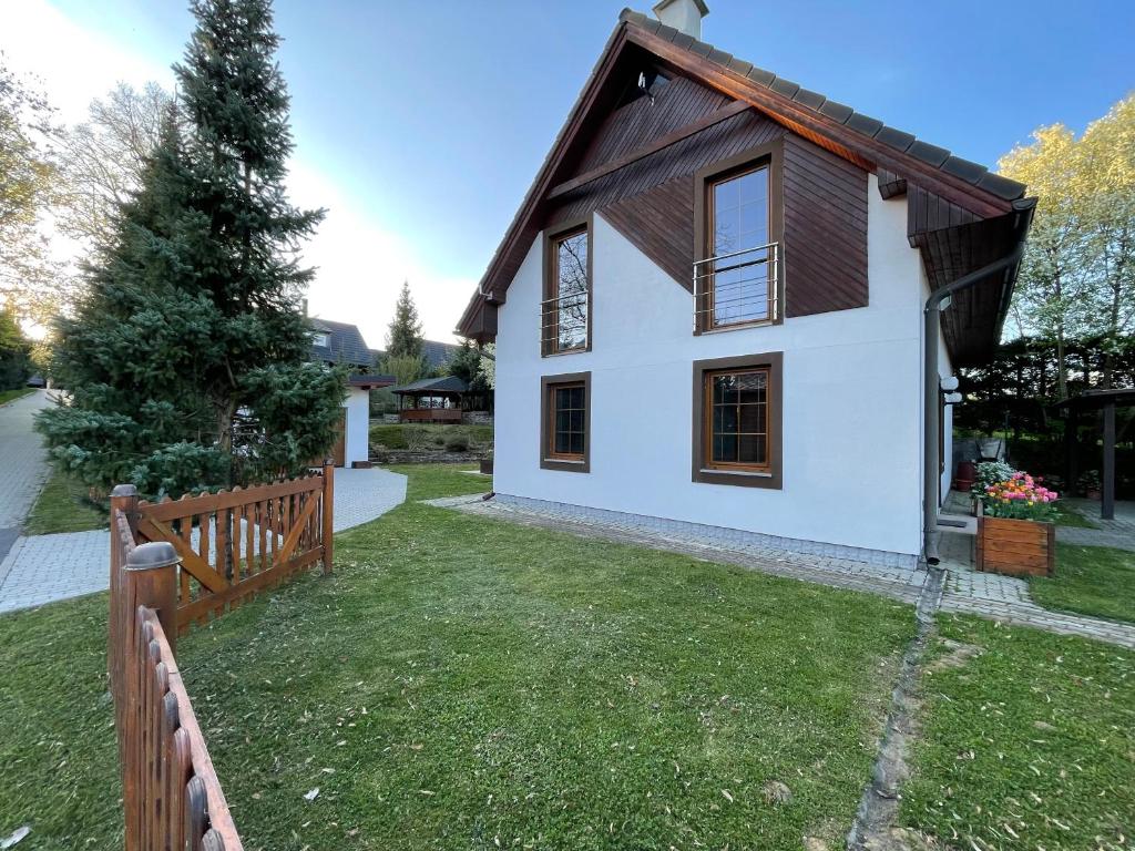 a small white house with a wooden fence at INFINITA Bodice in Liptovský Mikuláš