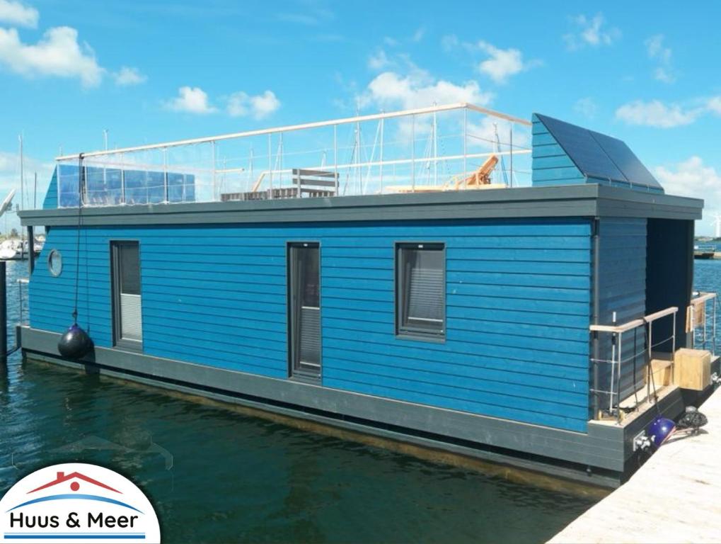 a blue house on a boat in the water at Hausboot Kaddi`s SunDREAM - Huus & Meer in Fehmarn
