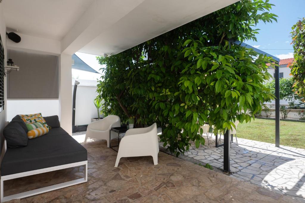 a living room with a couch and a tree at Holiday Home LI-ZA in Privlaka