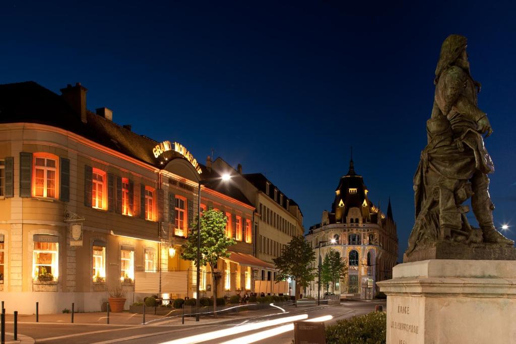 a statue in front of buildings at night at Best Western Premier Grand Monarque Hotel & Spa in Chartres