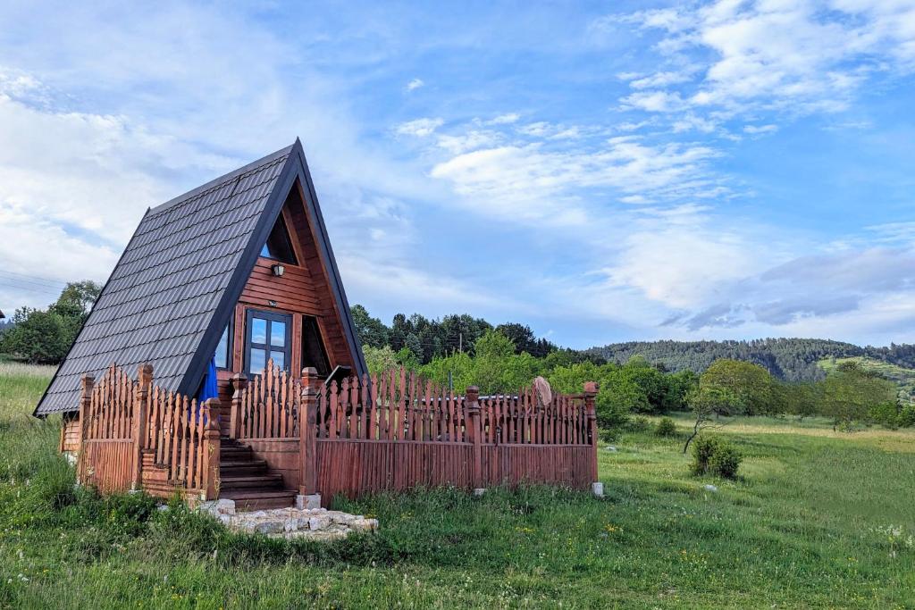 a small cabin in a field with a wooden fence at A Pine vikendica u srcu Zapadne Srbije in Nova Varoš