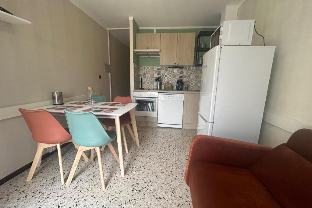 une cuisine avec une table, des chaises et un réfrigérateur dans l'établissement 2 rooms with your feet in the water, à Frontignan